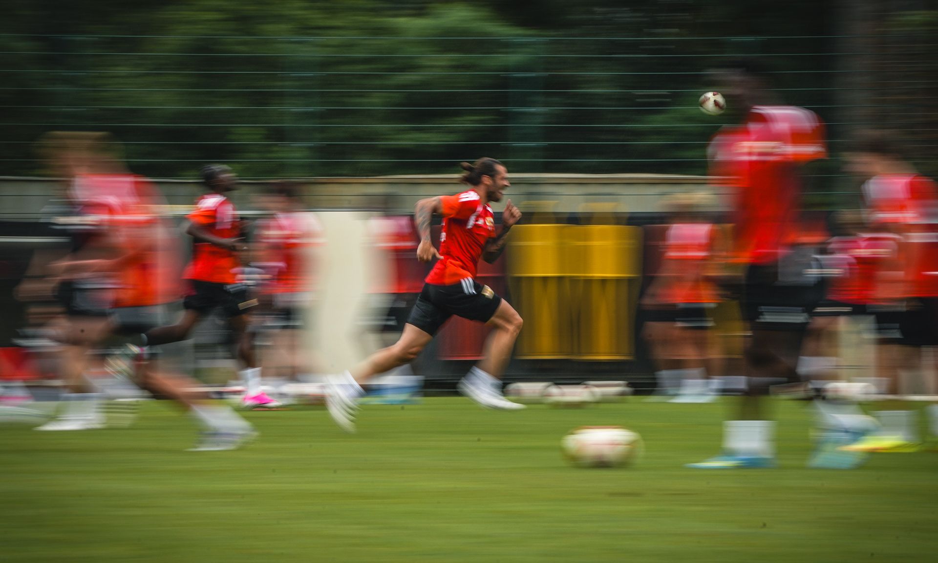 Spieler in roten Trikots sprinten auf einem Fußballfeld während des Trainings, der Hintergrund ist verschwommen.