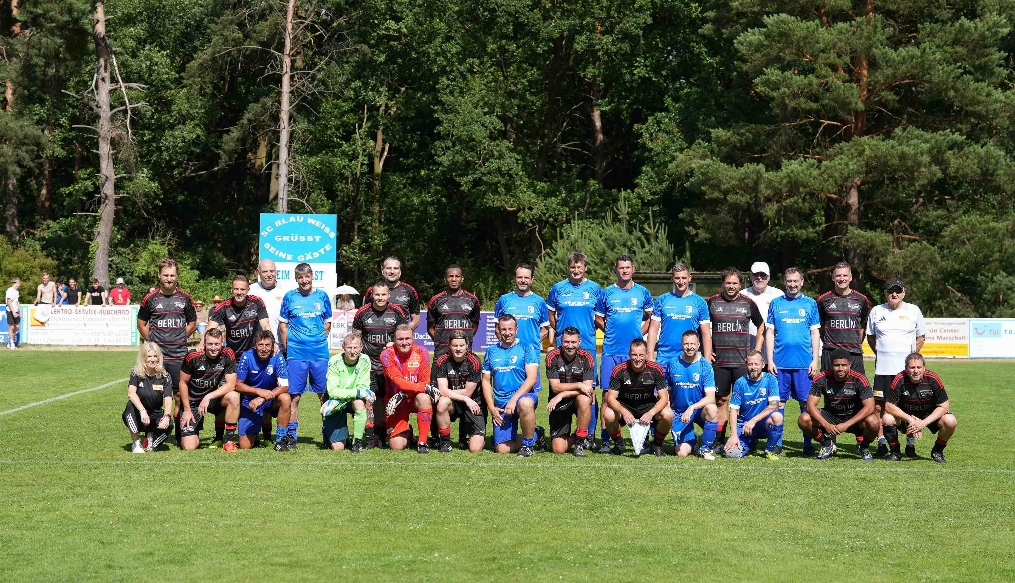 Gruppenszenen von Spielern in blauen und schwarzen Trikots auf einem Fußballplatz, umgeben von Bäumen und Zuschauern.
