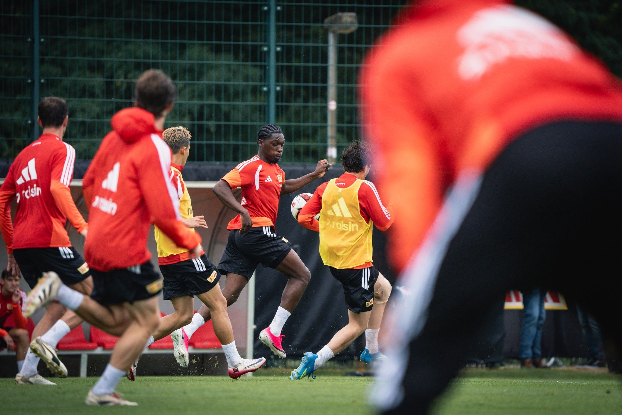Eine Gruppe von Fußballspielern trainiert auf einem Platz, während einer den Ball führt.