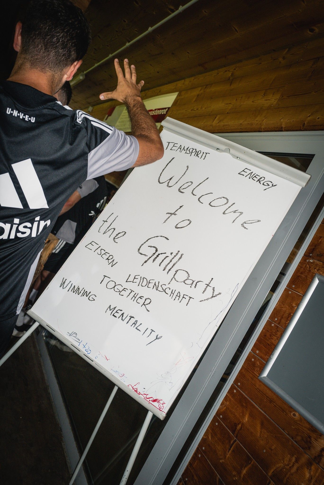 Ein Mann zeigt auf ein Flipchart mit der Aufschrift "Welcome to the Grillparty" und weiteren motivierenden Begriffen.