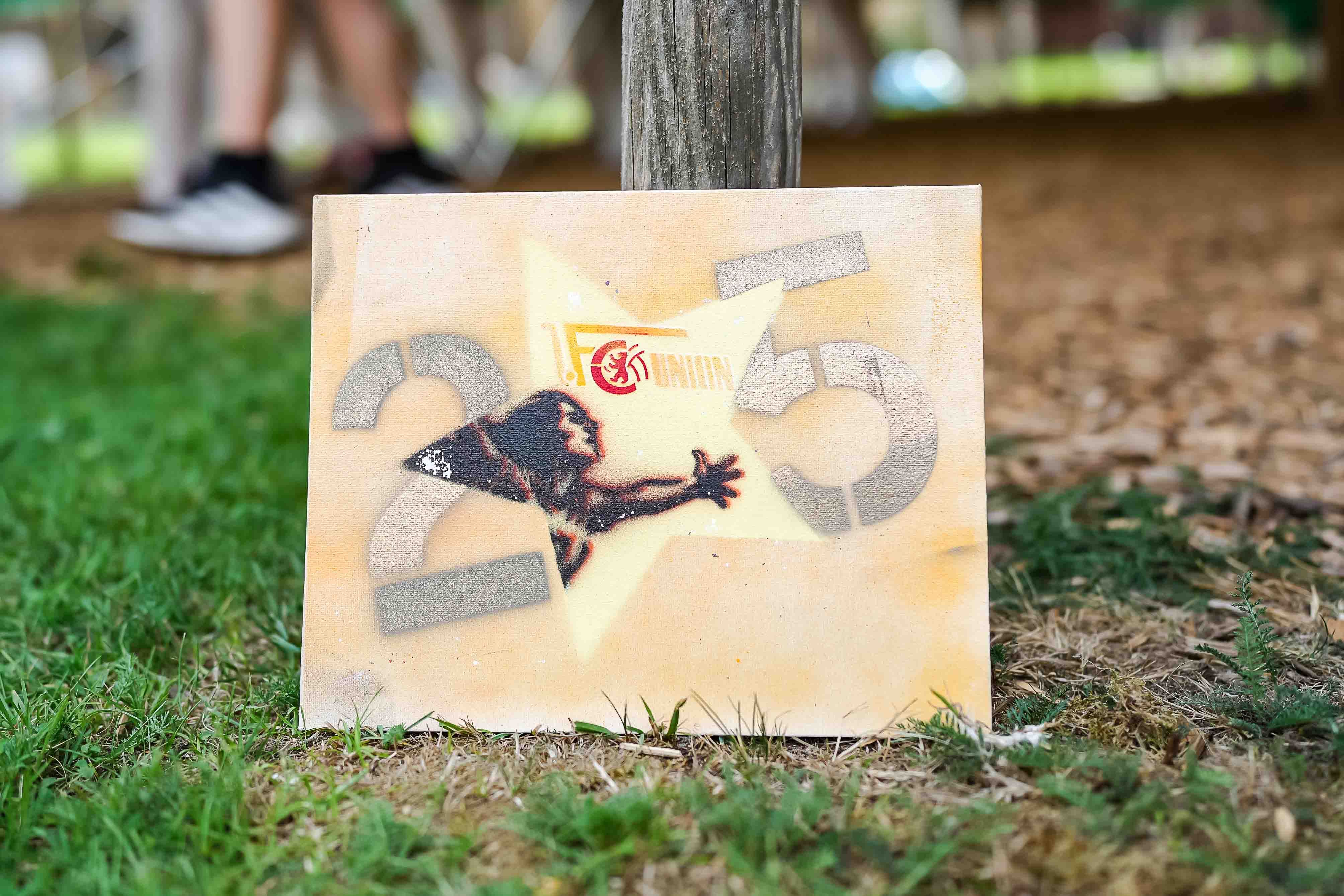 Graffiti auf einem Holzstück mit einer stilisierten menschlichen Figur und der Zahl 235 vor einem hellen Hintergrund.