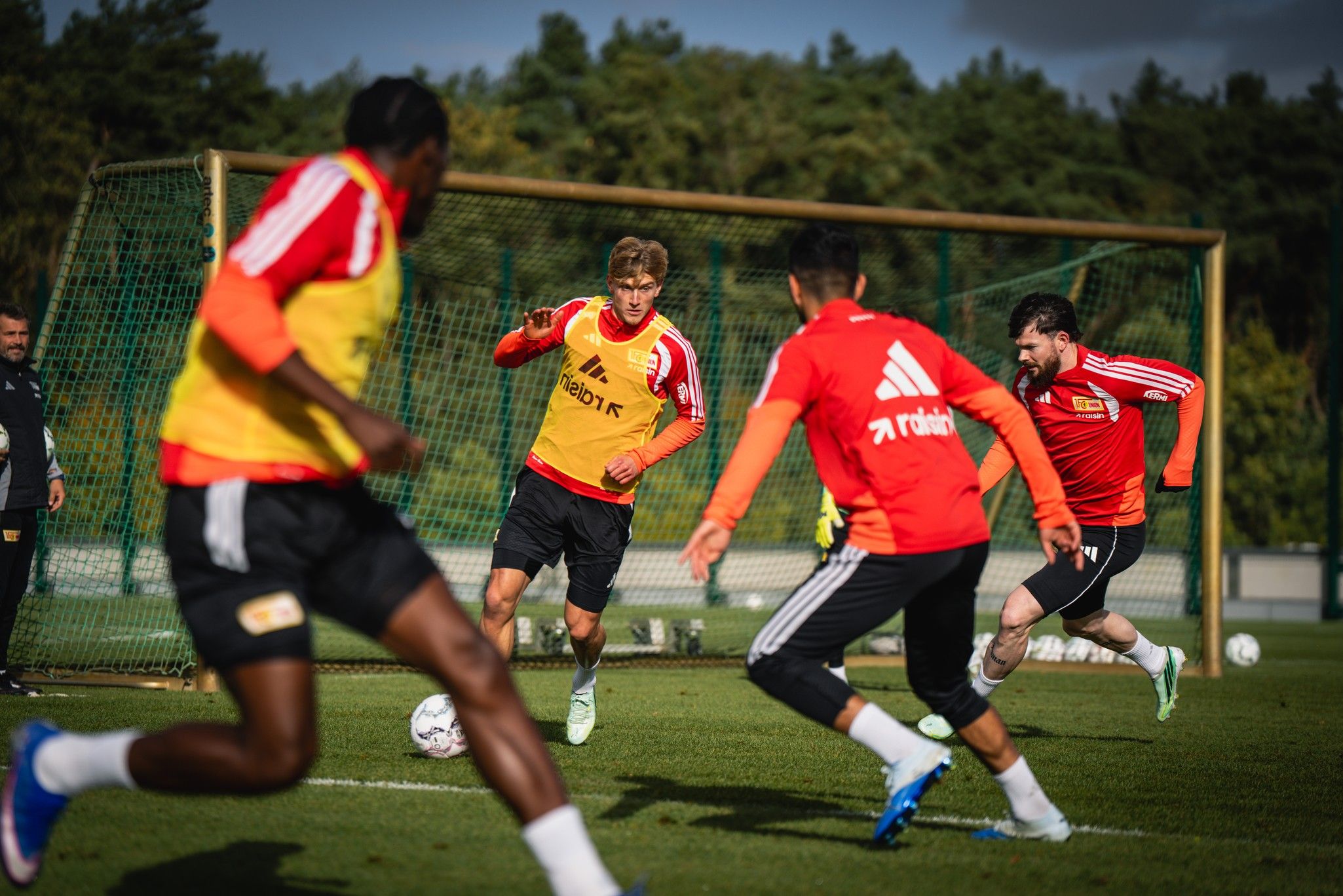 Mehrere Fußballspieler in Training, die sich auf einem Rasenfeld bewegen und miteinander passen.
