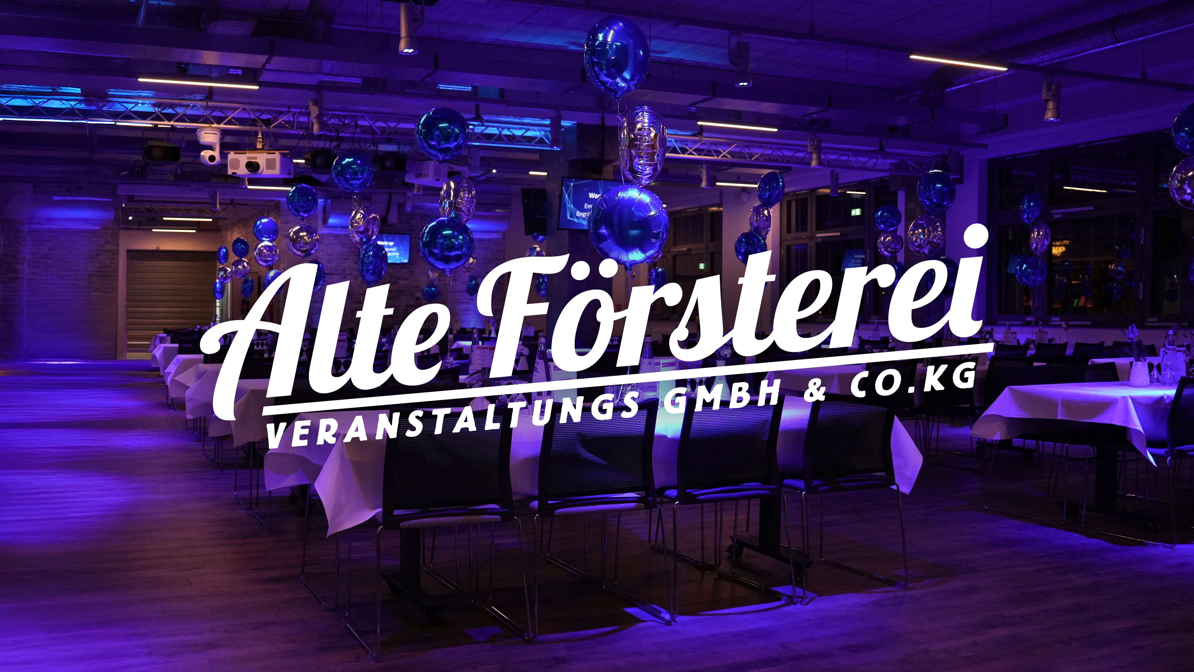 Ein stilvoller Veranstaltungsraum mit Tischen, Dekoration und einer Beleuchtung in Blau. Logo der Alten Försterei im Vordergrund.