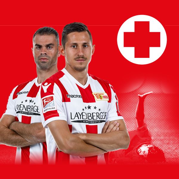 Zwei Fußballspieler in weißen Trikots mit rotem Hintergrund und einem rot-weißen Kreuz-Symbol.