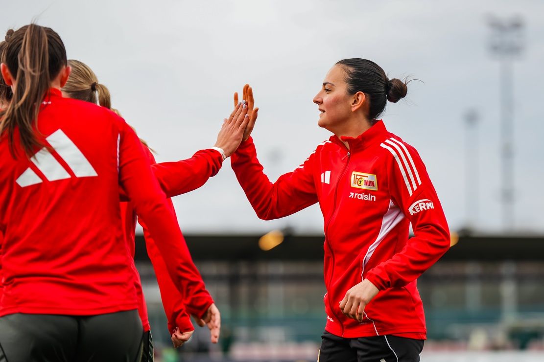 Teilnehmerinnen eines Fußballtrainings oder -spiels geben sich gegenseitig Höchstleistungen mit Anerkennung in roten Trikots.