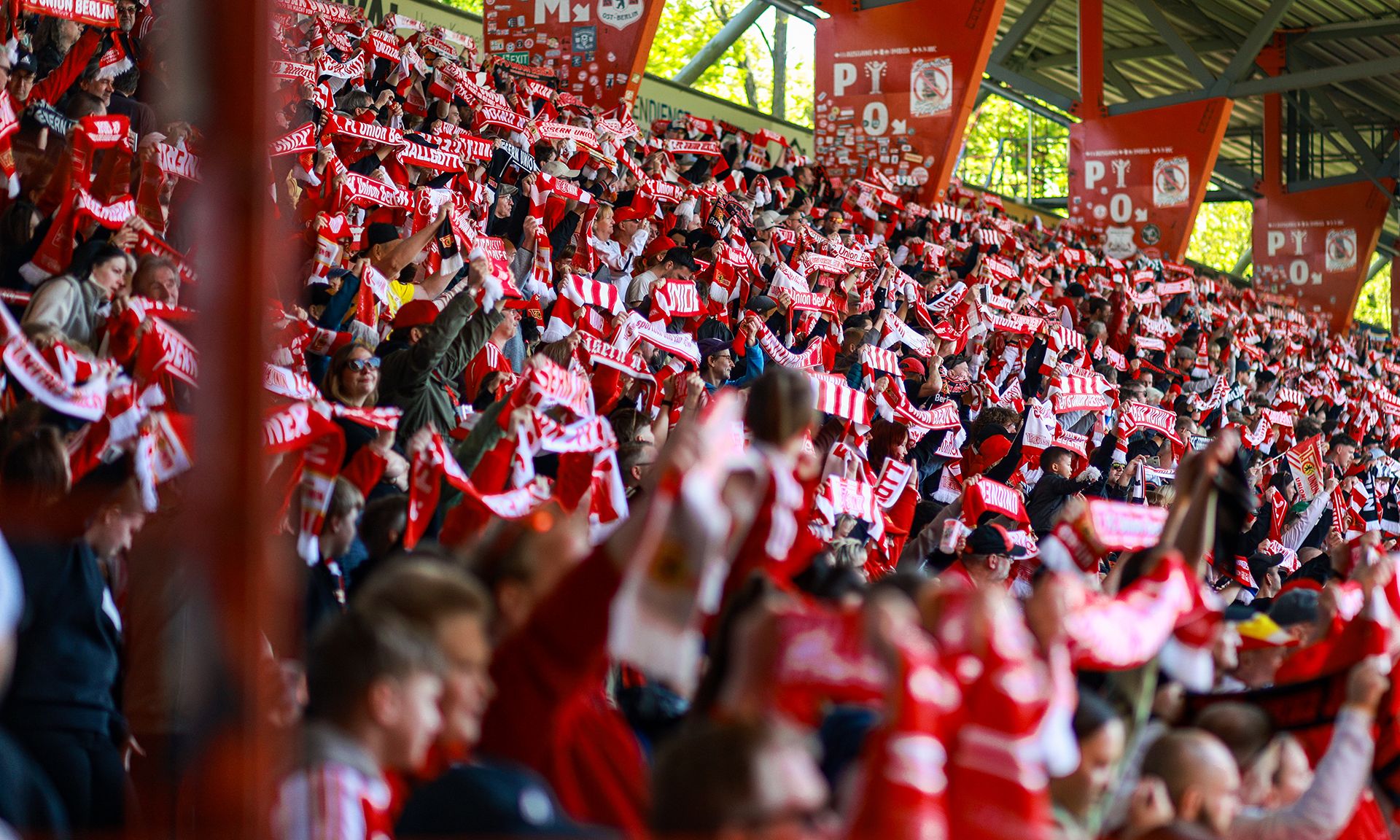 Eine große Menschenmenge im Stadion schwenkt rote und weiße Schals und zeigt Begeisterung während eines Spiels.