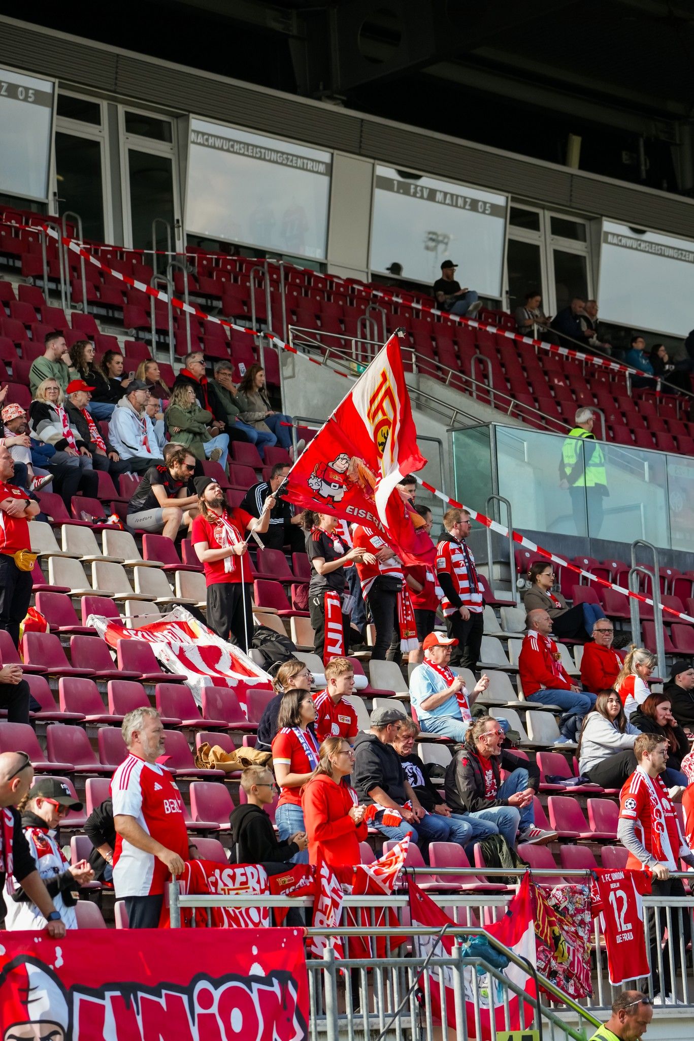 Spectators in a stadium show team colors and wave flags while watching a game.