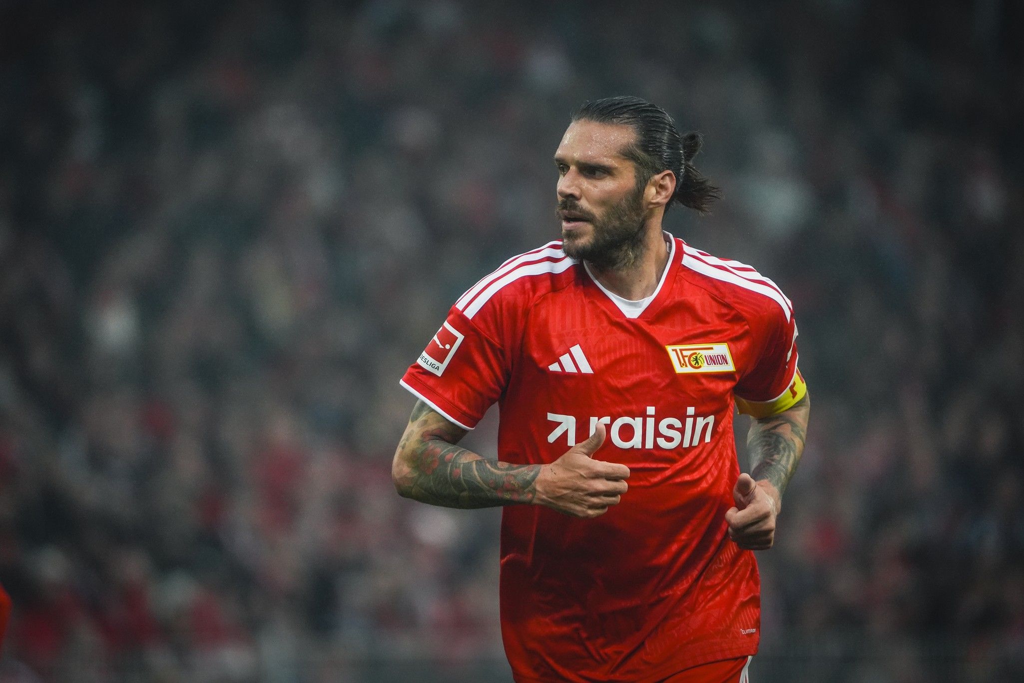 Ein Fußballspieler in roter Uniform mit dem Schriftzug "raisins" joggt auf dem Spielfeld.