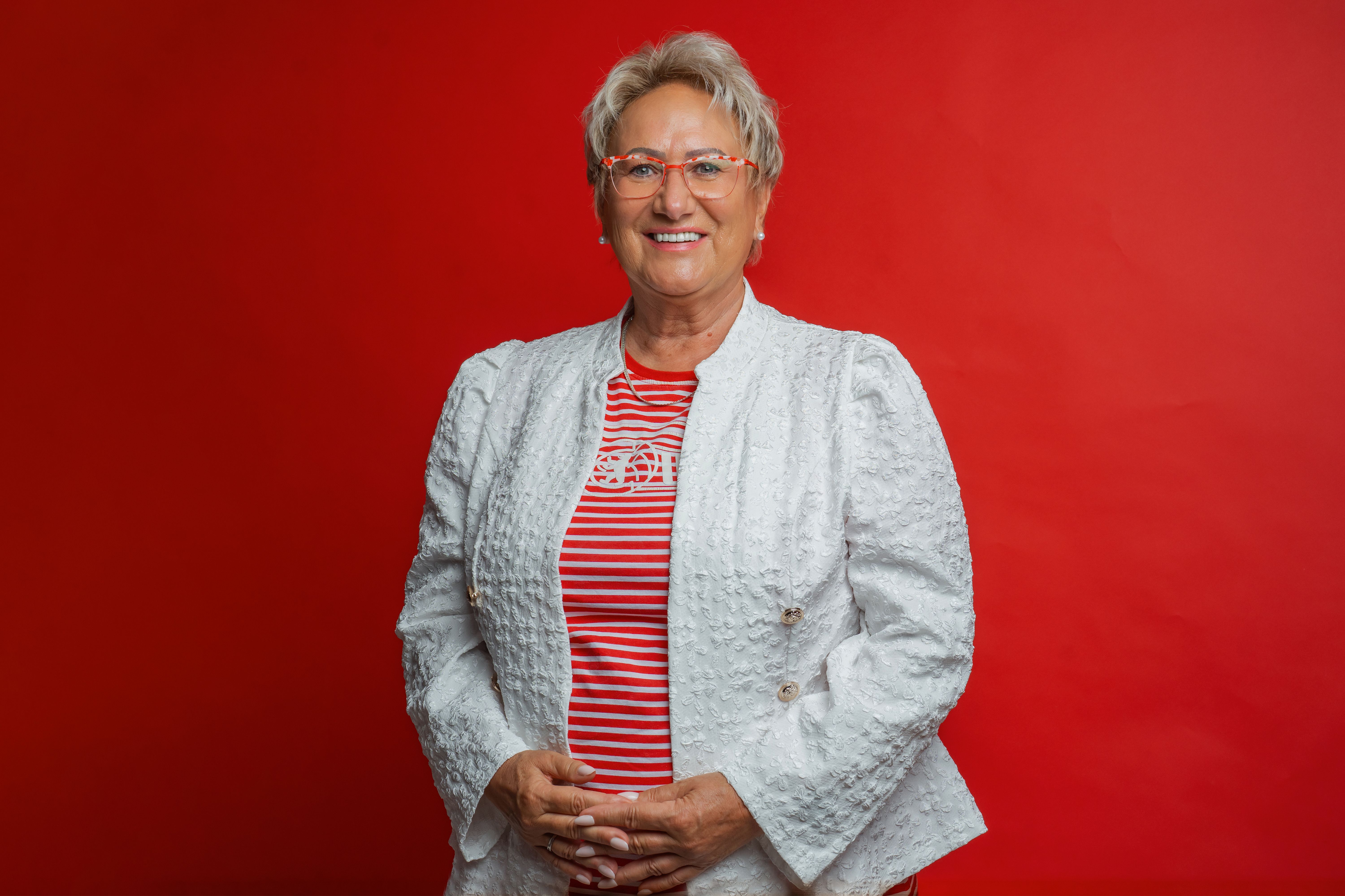 Ein Bild von Sylvia Weisheit. Sie steht vor einer roten Wand.