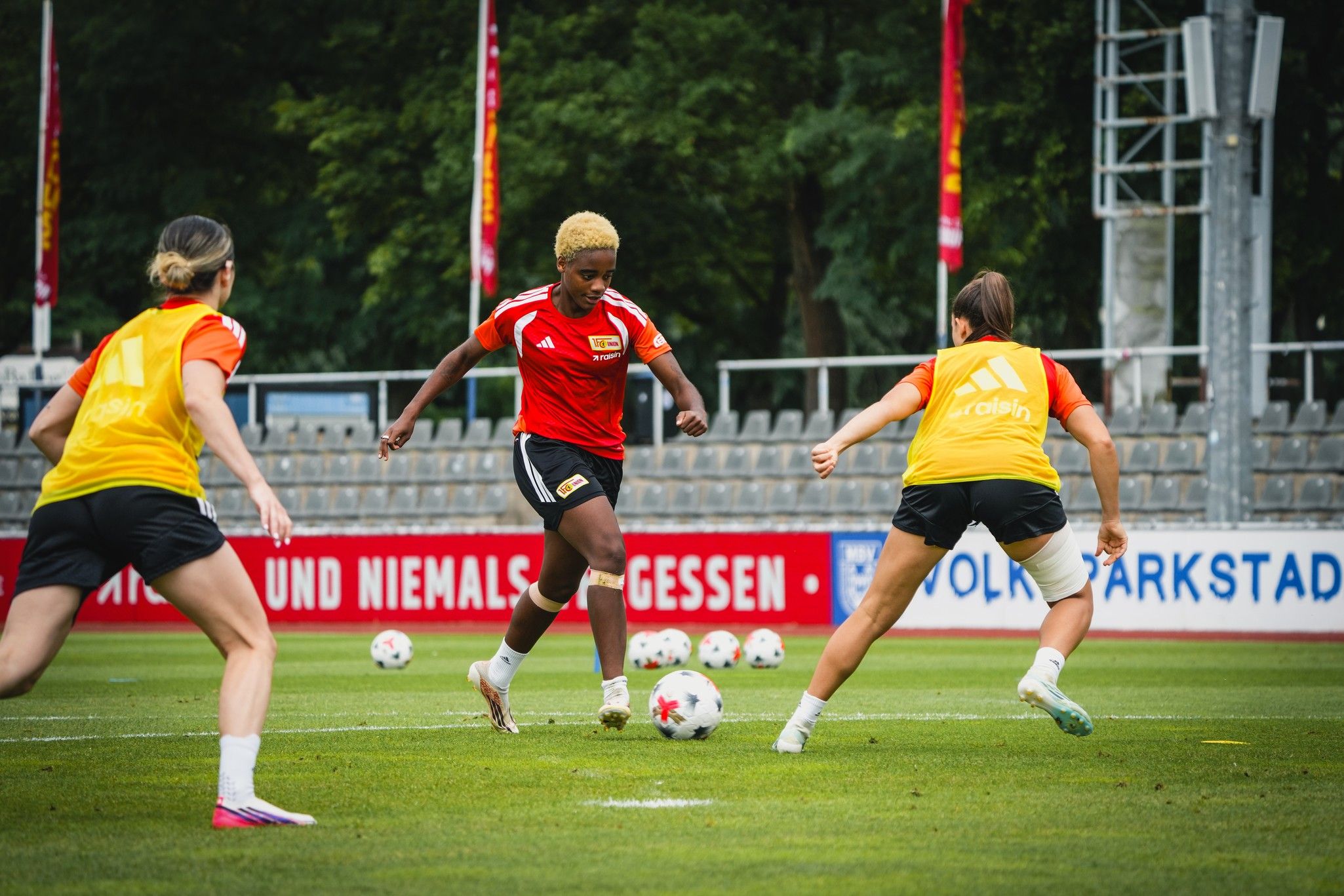 Zwei Fußballspielerinnen in Trainingskleidung dribbeln den Ball auf einem Fußballplatz während eines Trainings.