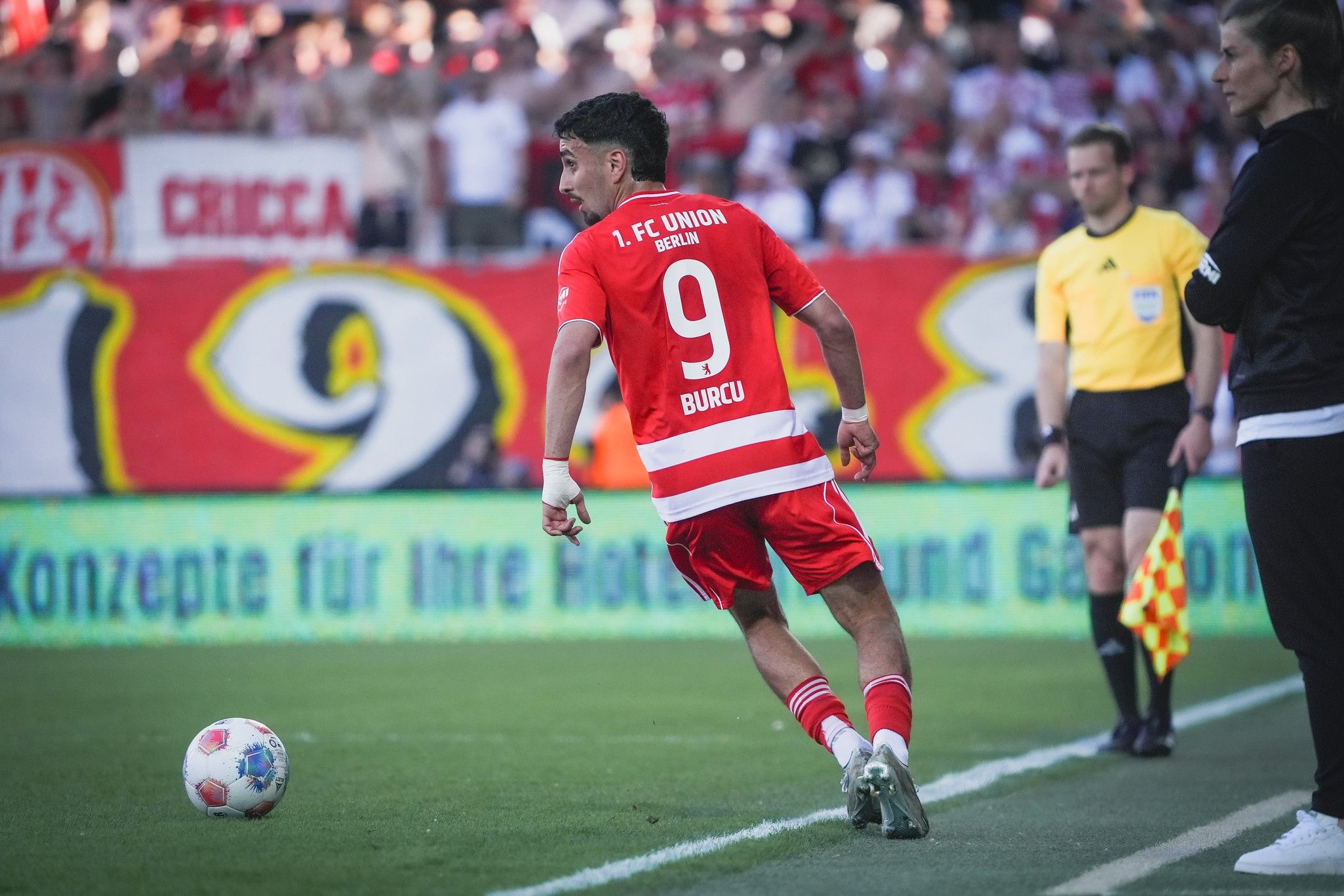 Ein Spieler des 1. FC Union Berlin mit der Nummer 9, in Rot und Weiß, läuft am Spielfeldrand entlang.