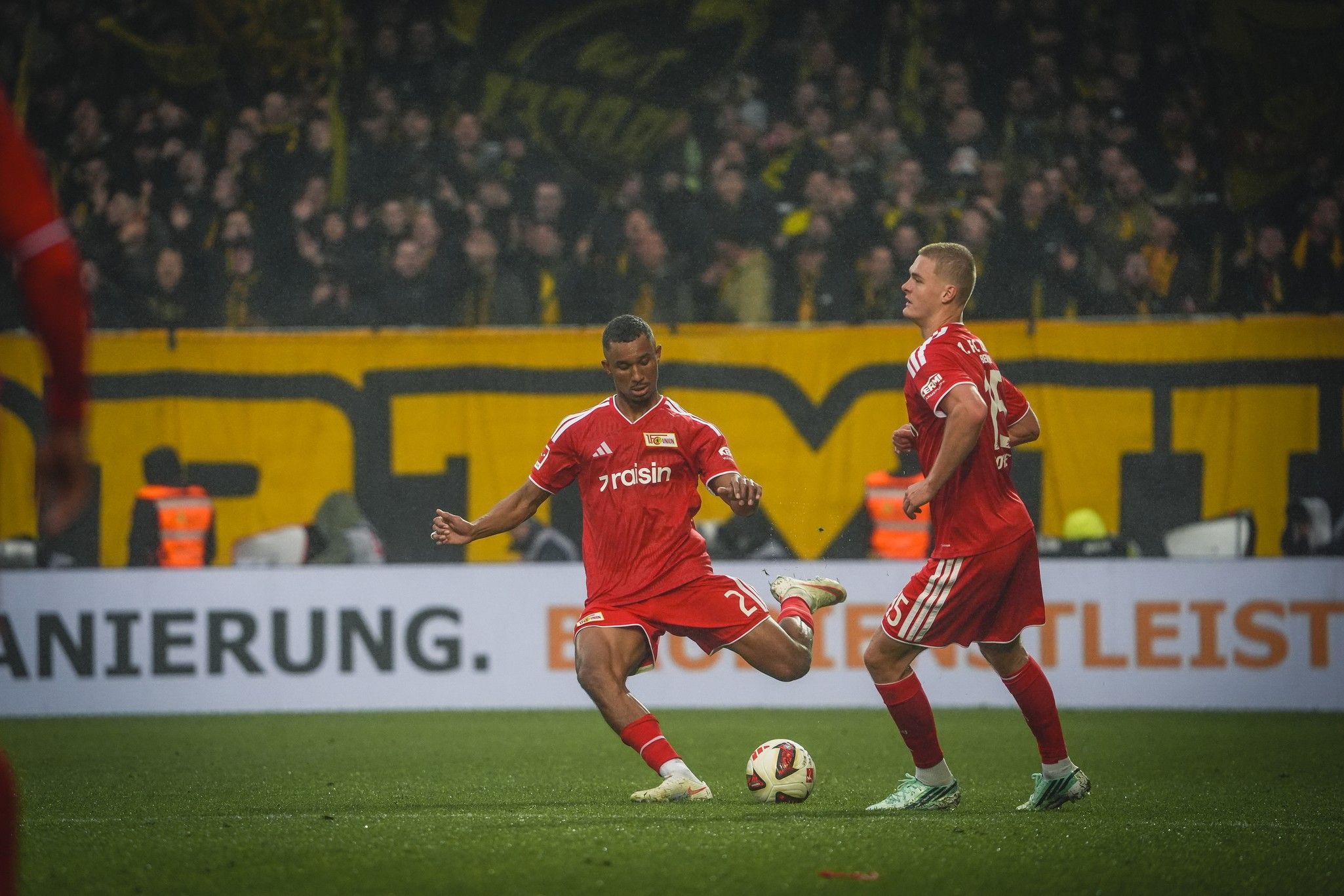 Fußballspieler von Union Berlin in roten Trikots während eines Spiels, eine actiongeladene Szene auf dem Spielfeld.
