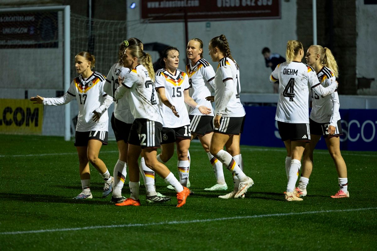 Mannschaft feiert einen Treffer auf dem Platz, Trikots in Schwarz, Rot und Gold, Sportveranstaltung bei Nacht.