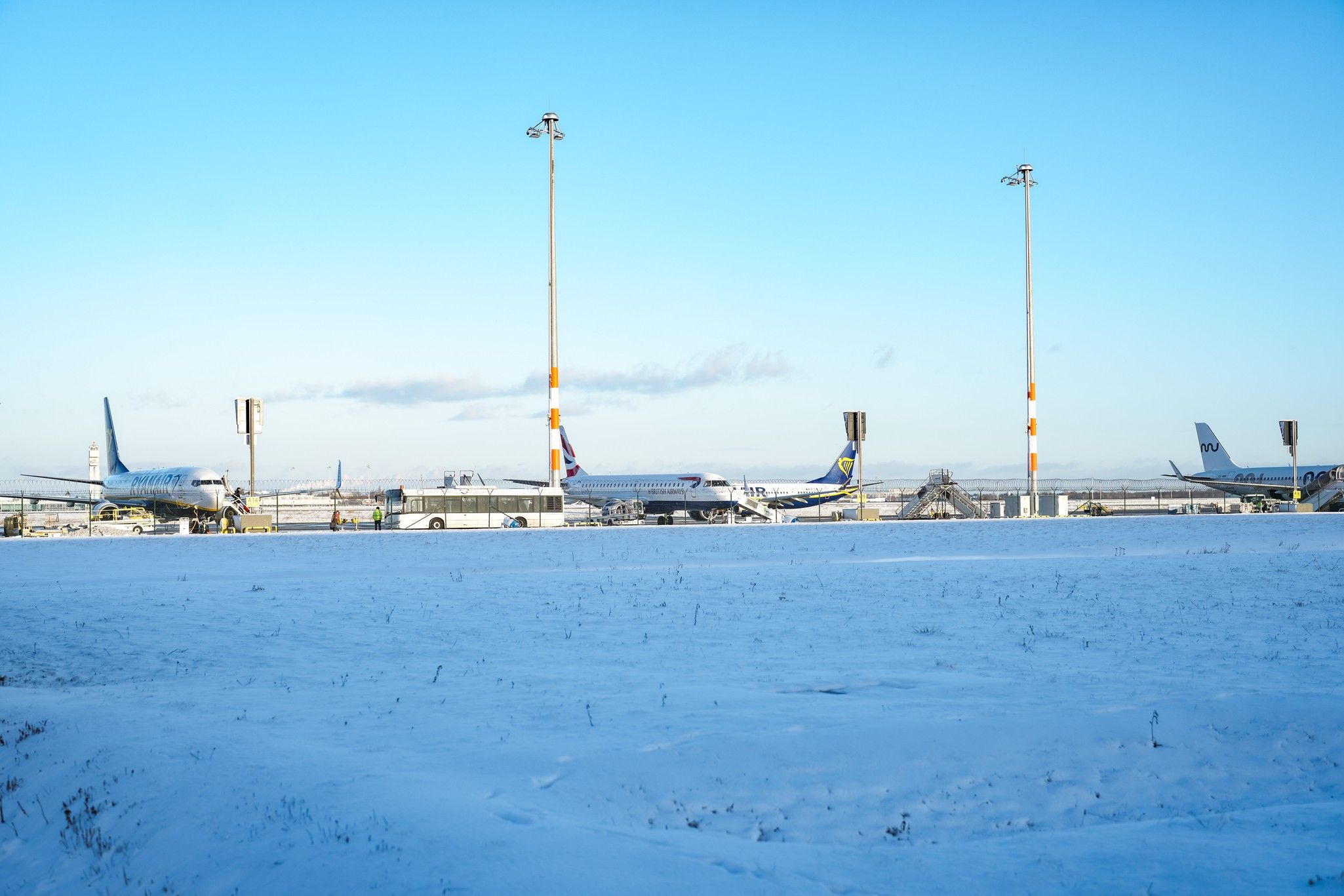 Flughafen mit mehreren Flugzeugen auf dem Rollfeld, umgeben von Schnee und klarem, blauem Himmel.