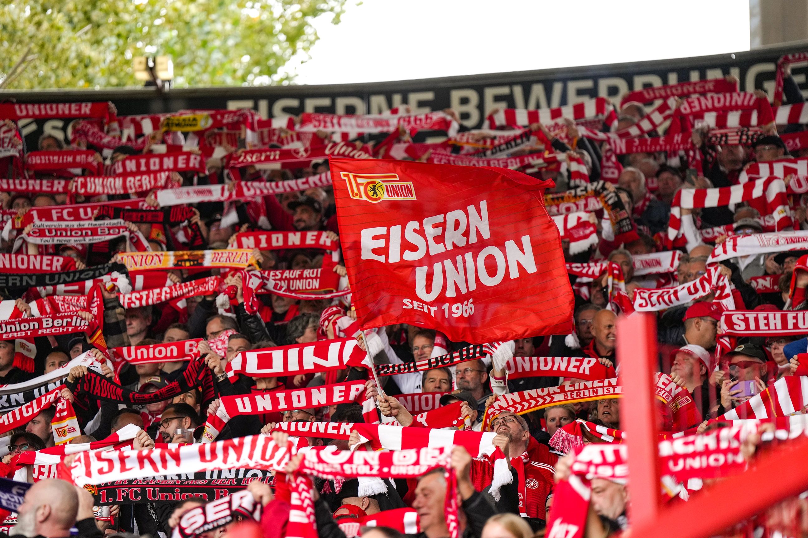 Eine große Menschenmenge in einem Stadion schwenkt rote Schals mit den Aufschriften "EISERN UNION" und "UNION".