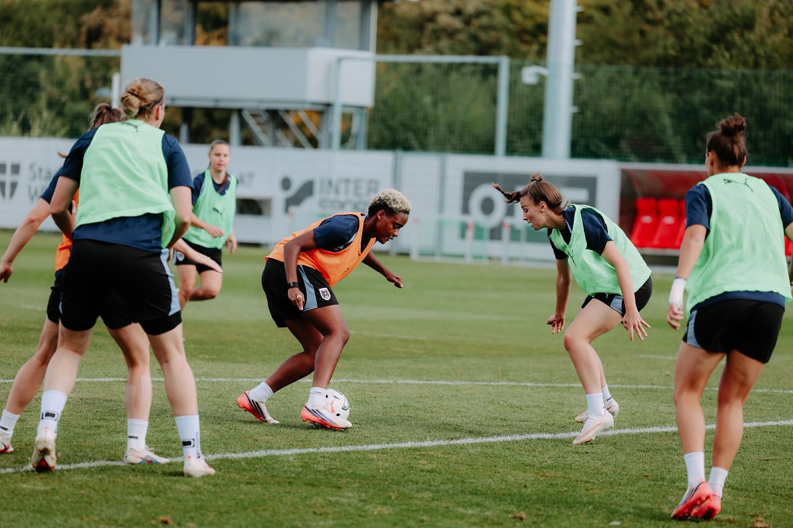 Frauenfußballmannschaft trainiert auf dem Platz, Spielerinnen absolvieren Dribbling-Übungen.