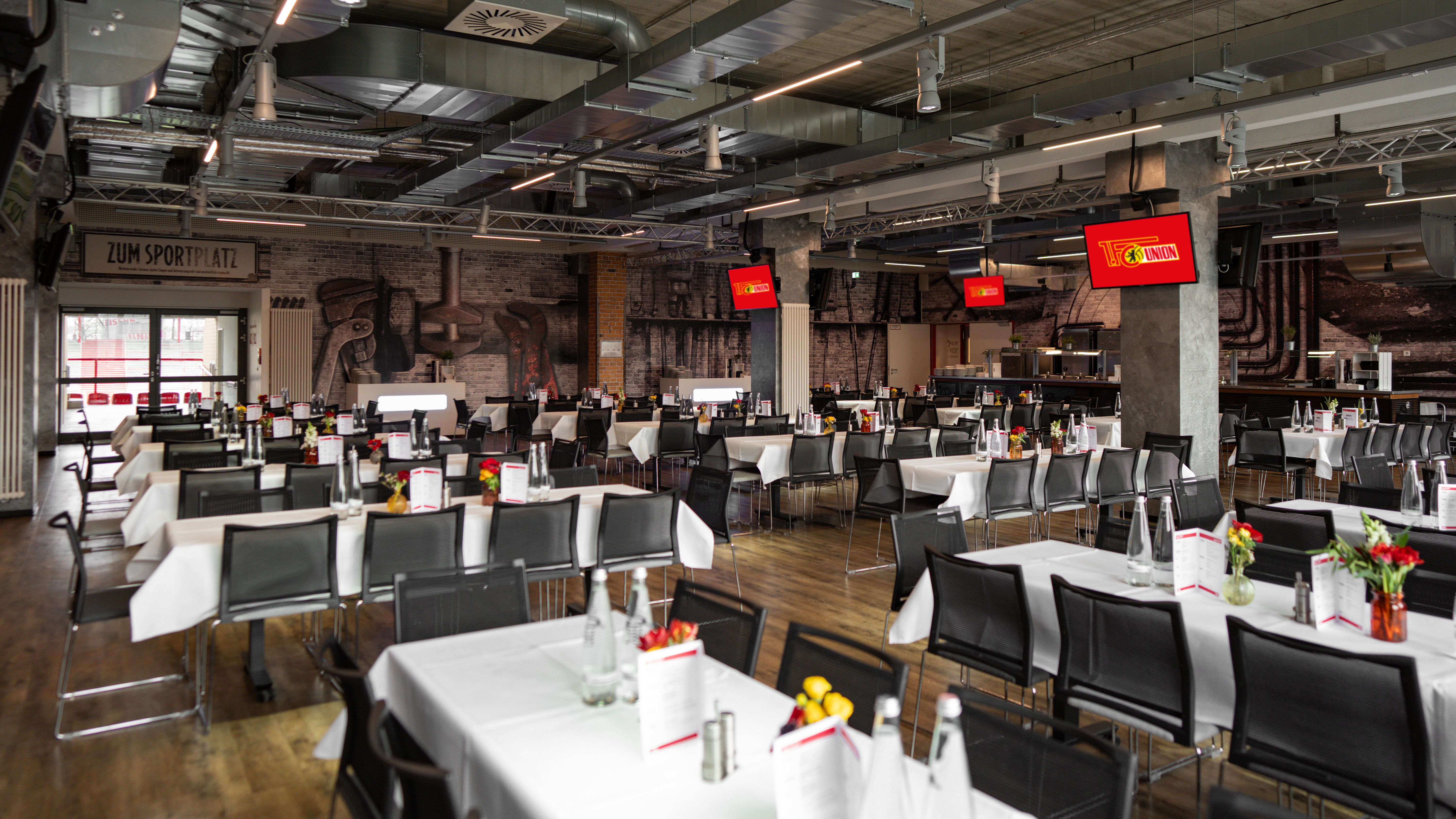 Innenansicht eines modernen Restaurants mit Tischen, bestückt mit weißen Tischdecken, Menükarten und Blumendekoration.