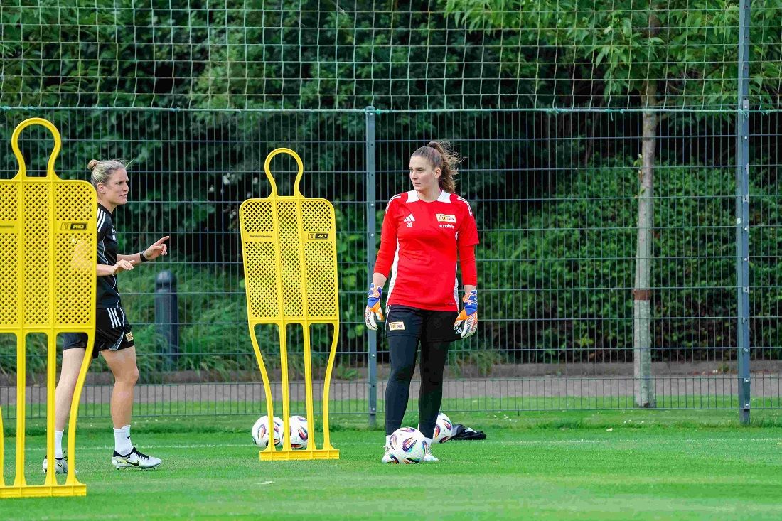 Zwei Fußballspielerinnen üben auf einem Trainingsplatz mit Trainingshilfen und Bällen.