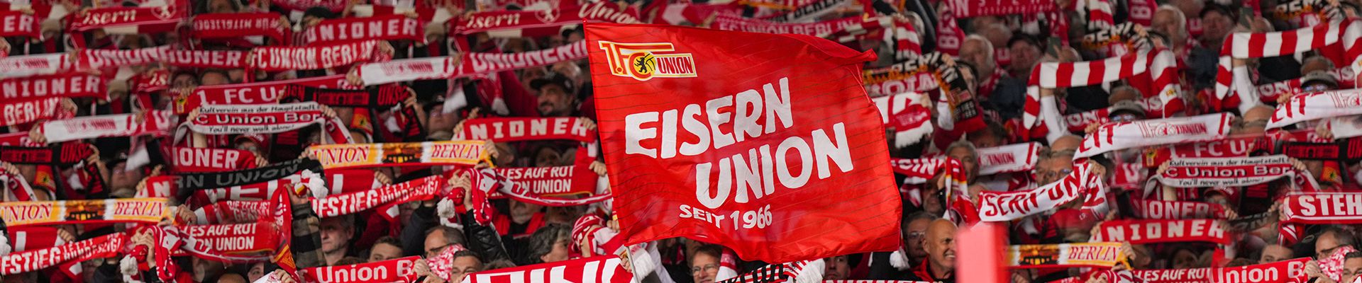 Fanfaren und Fans mit roten und weißen Schals und Fahnen, die die Mannschaft "Union" unterstützen.