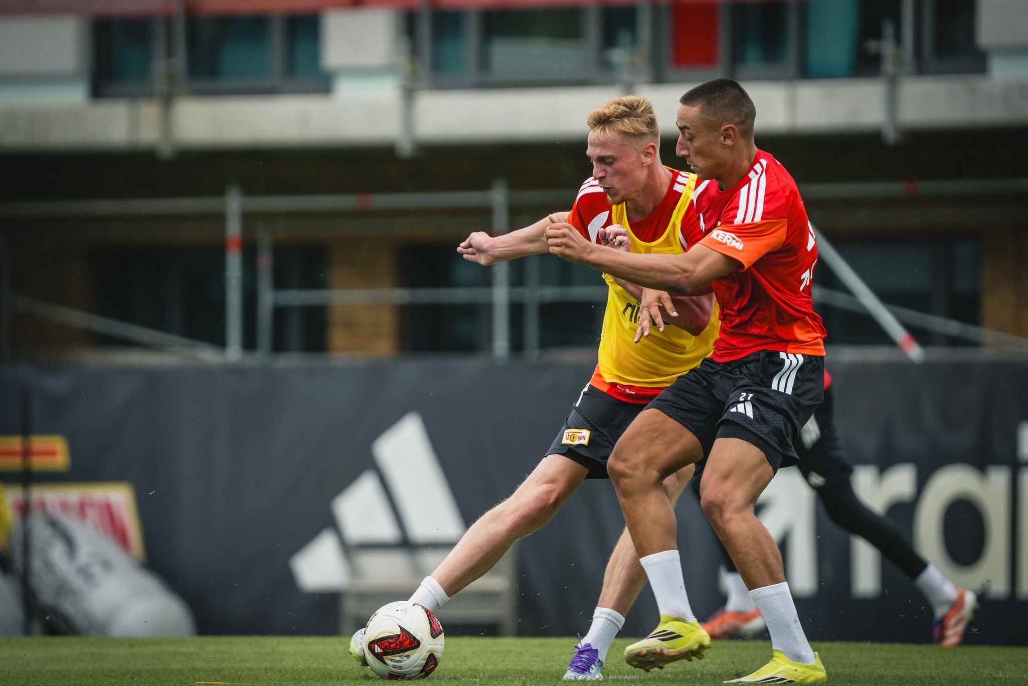 Zwei Fußballspieler im Wettkampf um den Ball während eines Trainings auf einem Sportplatz.