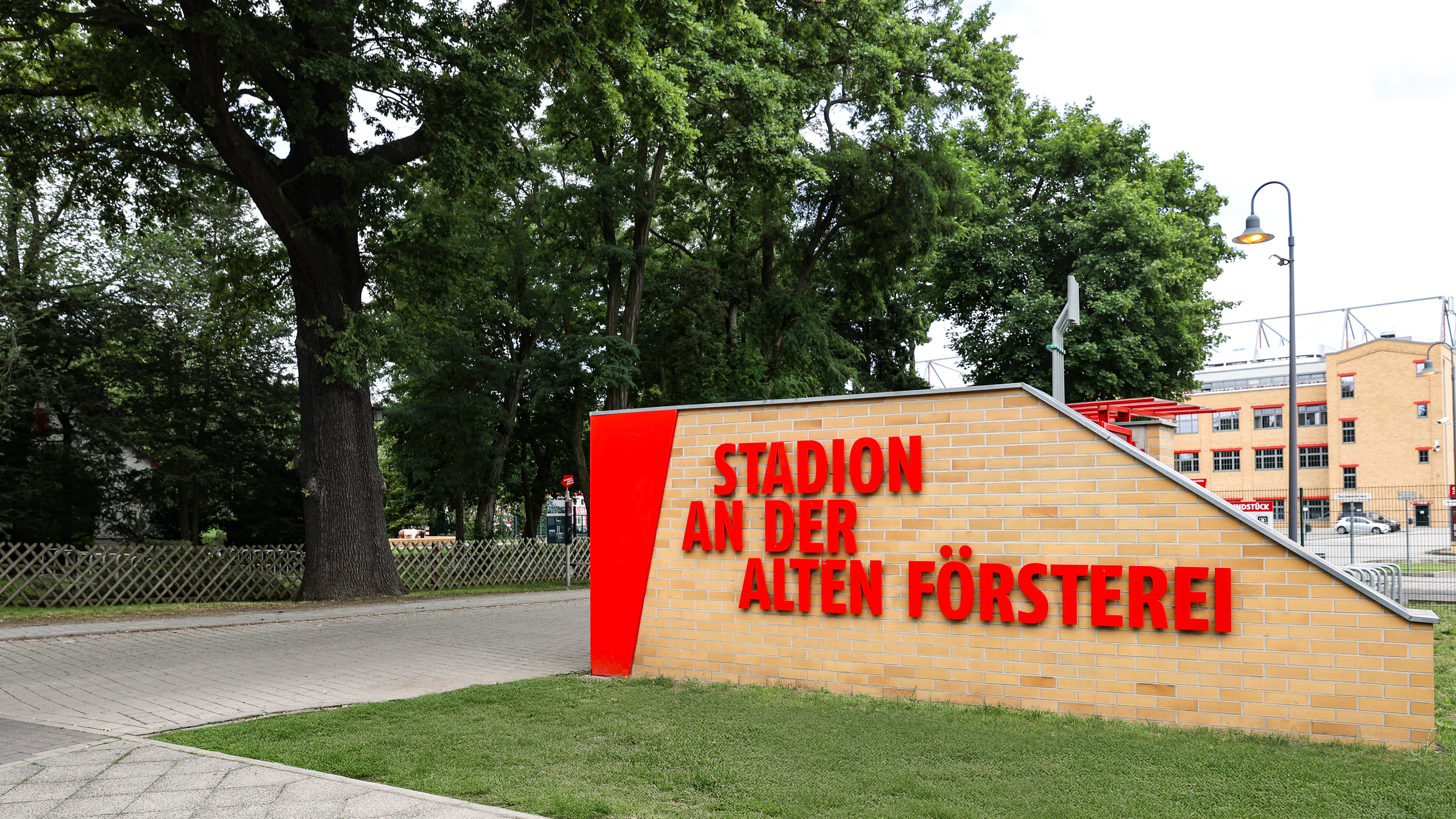 Stadion an der Alten Försterei, gelbes Mauerwerk mit rotem Schriftzug, umgeben von Bäumen und Grünflächen.