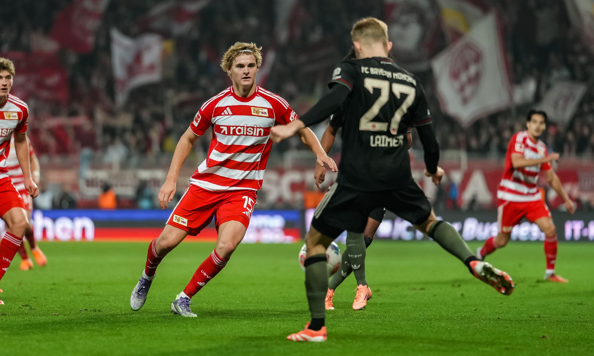 Ein Fußballspiel zwischen zwei Teams, Spieler in roten und weißen Trikots und ein Torwart in schwarzer Ausrüstung auf dem Spielfeld.