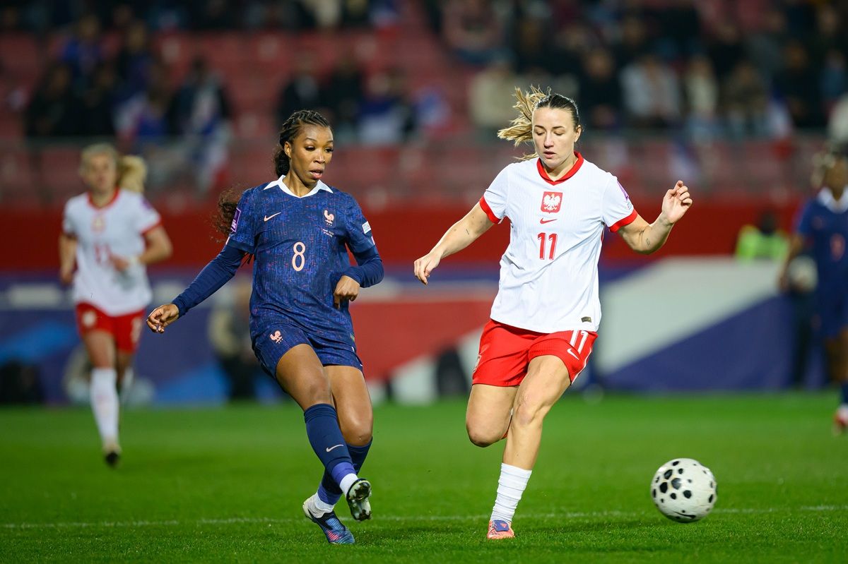 Zwei Fußballspielerinnen in Aktion während eines Spiels, eine trägt das Trikot von Frankreich, die andere das von Polen.