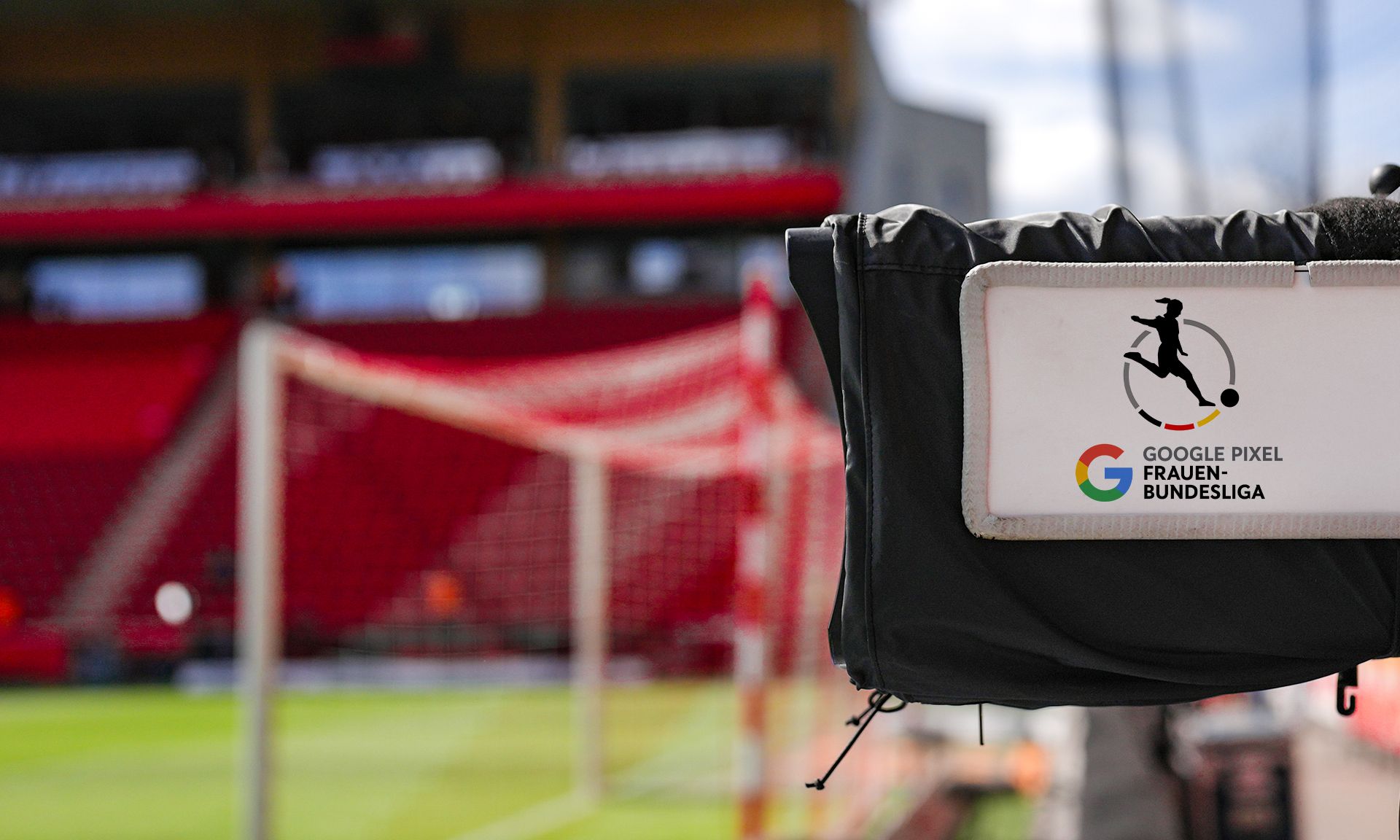 Kameraaufnahme mit dem Logo der Google Pixel Frauen-Bundesliga im Vordergrund, im Hintergrund ein Fußballfeld und Tribünen.