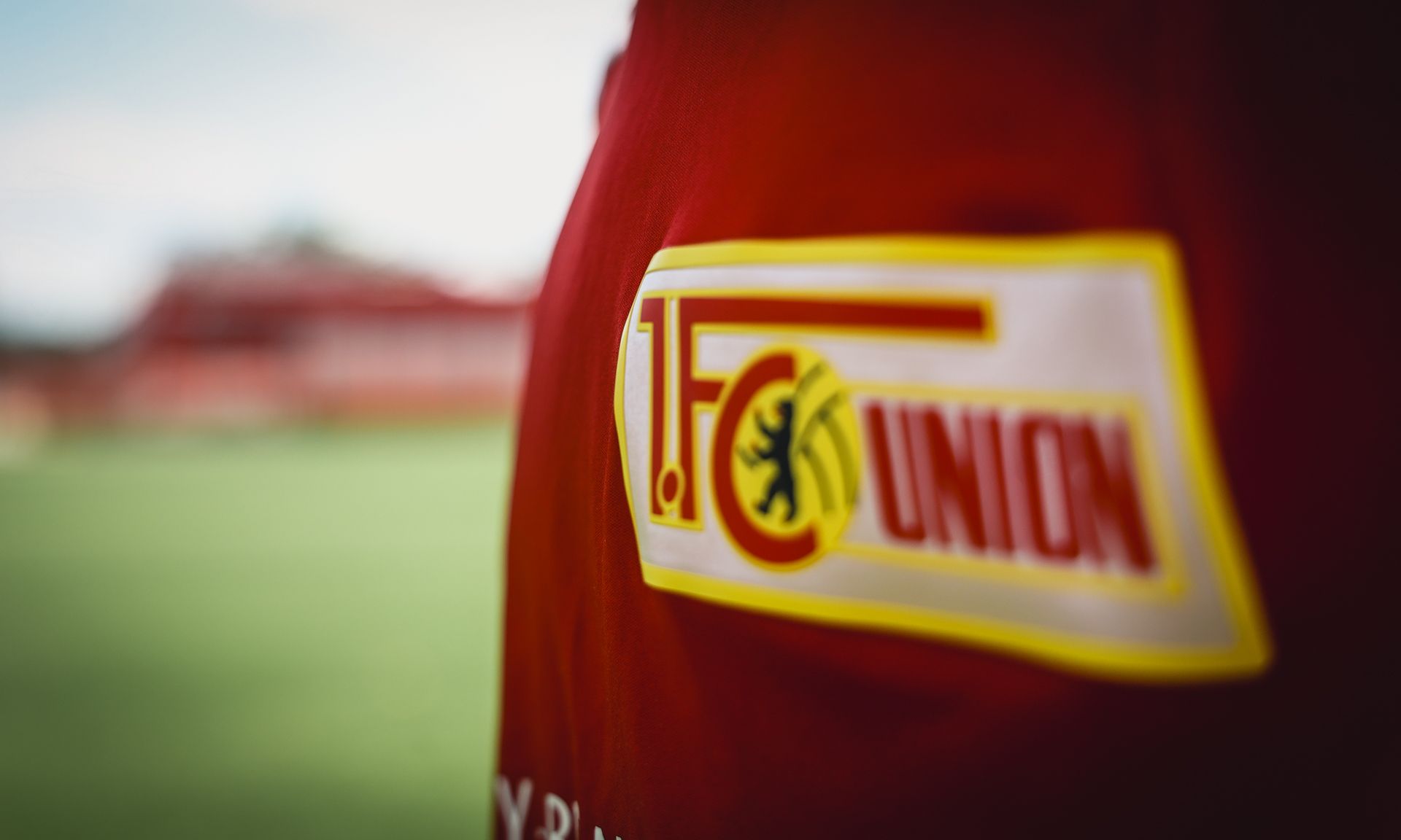 Logo des 1. FC Union Berlin auf einem roten Trikot, teilweise unscharf im Vordergrund.