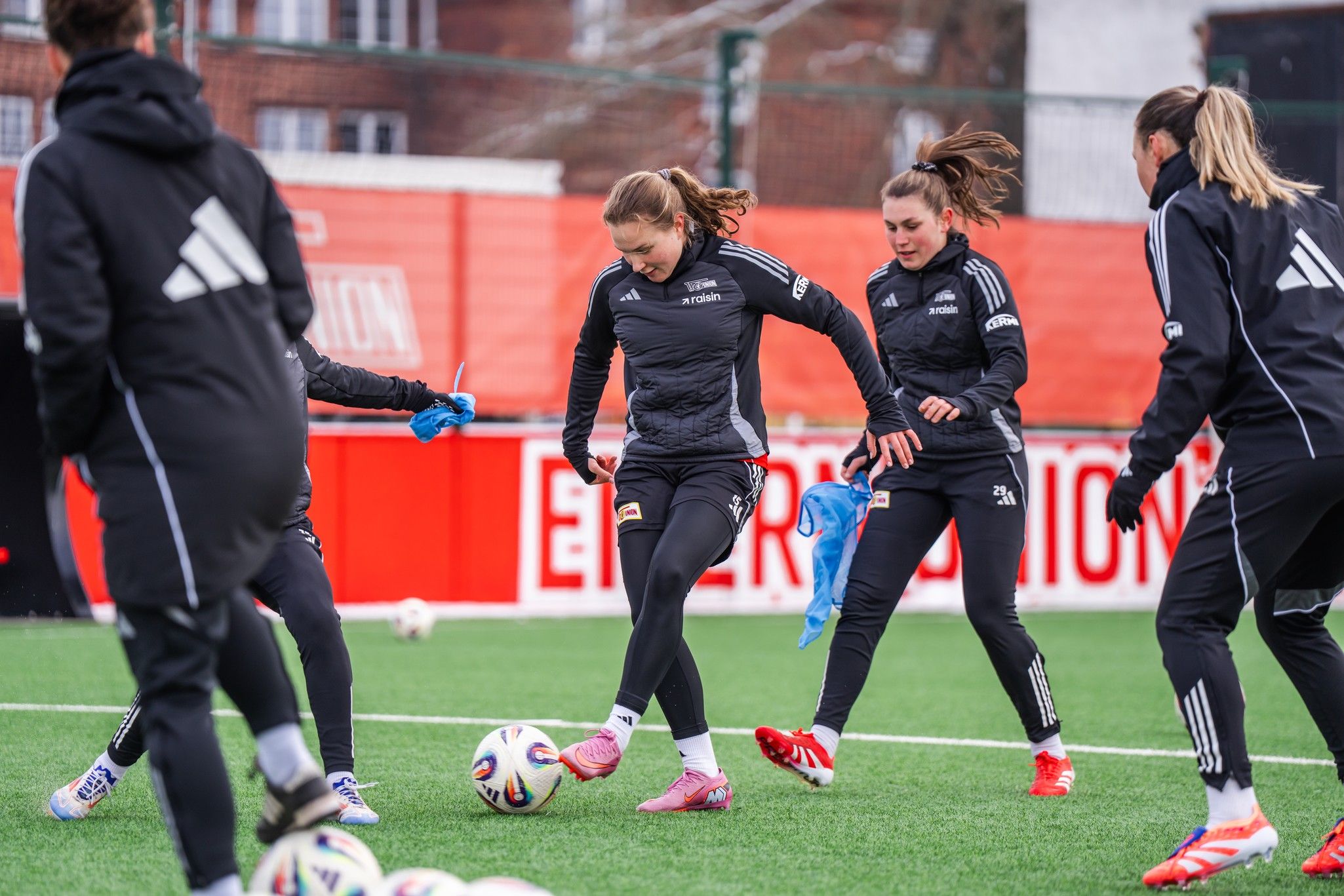 Frauenfußballmannschaft in Training, Spielerinnen führen Übungen mit dem Ball auf einem Kunstrasenplatz durch.