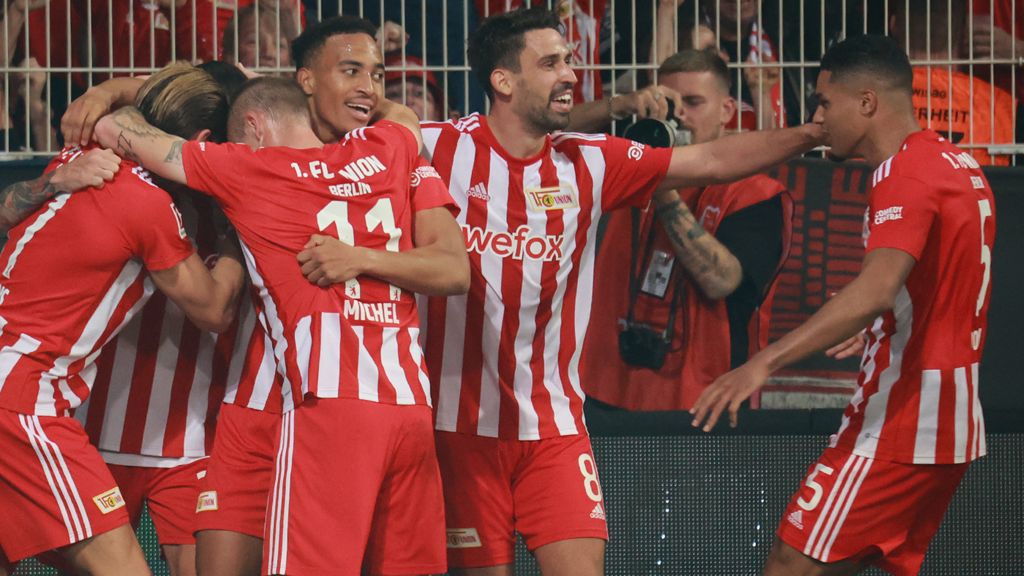 Spieler von Union Berlin jubilieren nach einem Tor, umarmt und feiert zusammen auf dem Spielfeld.