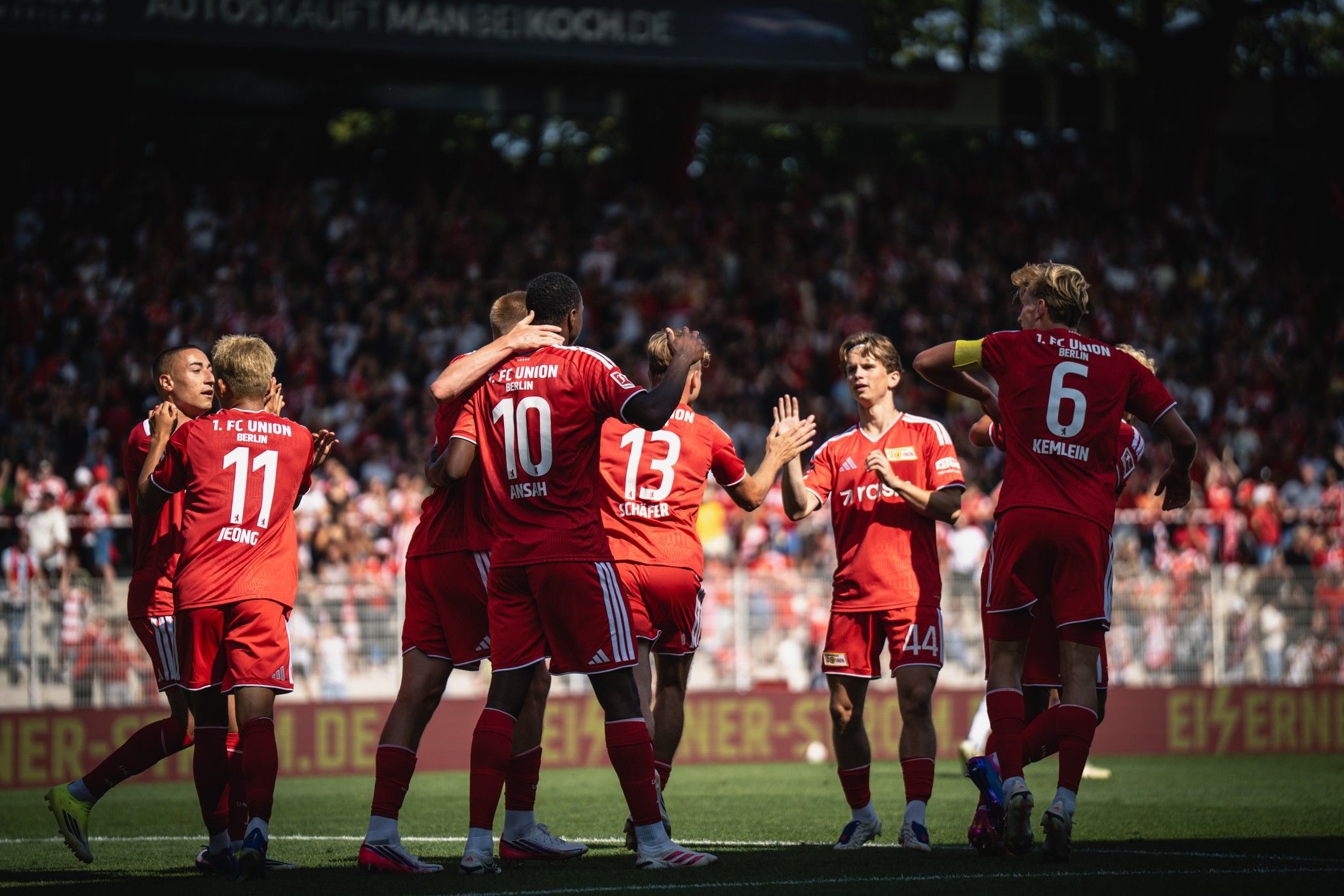 Spieler des 1. FC Union Berlin feiern ein Tor in einem Stadion vor jubelndem Publikum.