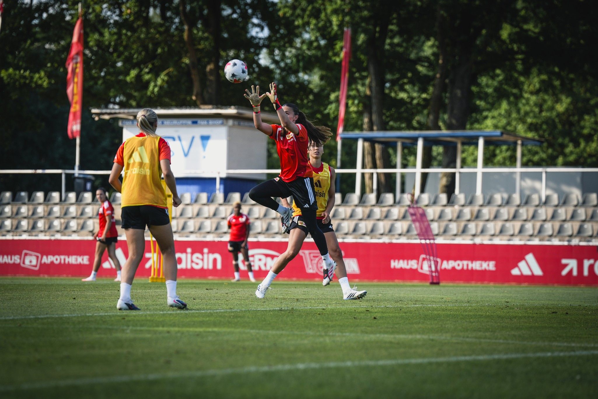 Eine Fußballspielerin springt, um den Ball während eines Trainings zu fangen, während andere Spielerinnen zuschauen.
