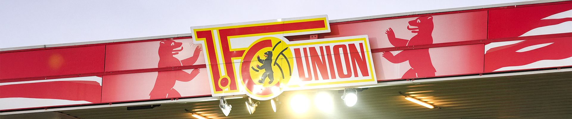 Logo des FC Union Berlin auf einem Stadiongebäude, umgeben von dekorativen roten Elementen.