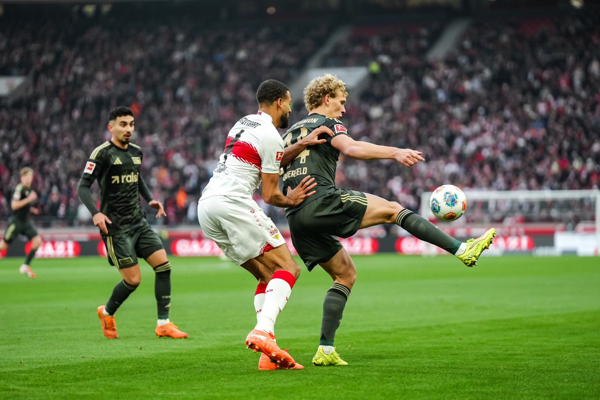 Zwei Fußballspieler in Aktion während eines Spiels, einer versucht den Ball zu kontrollieren, der andere setzt zur Abwehr an.