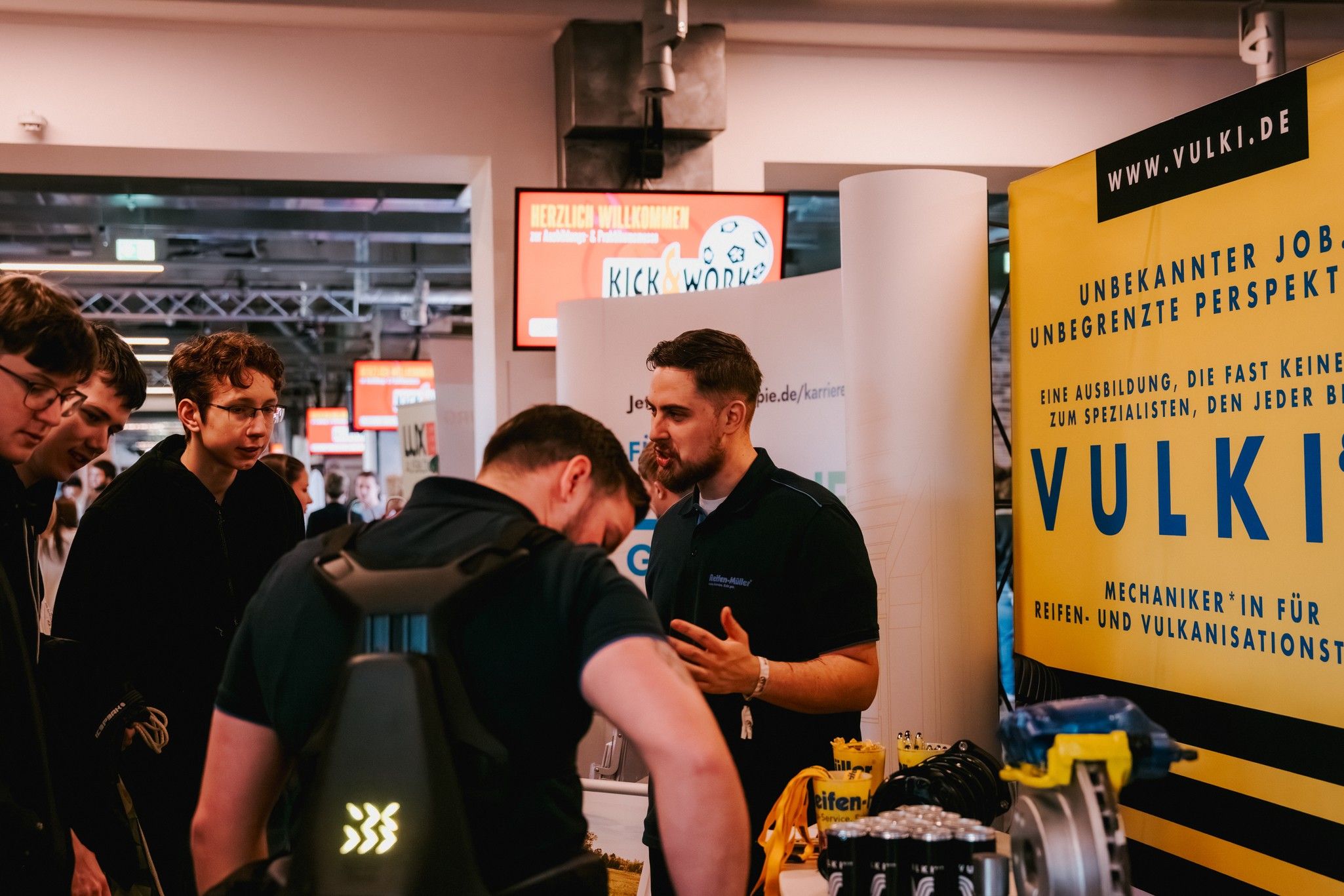 Ein Stand bei einer Messe mit einem Berater von VULKI, der Informationen über Ausbildungsplätze im Bereich Reifen- und Vulkanisationstechnik gibt.