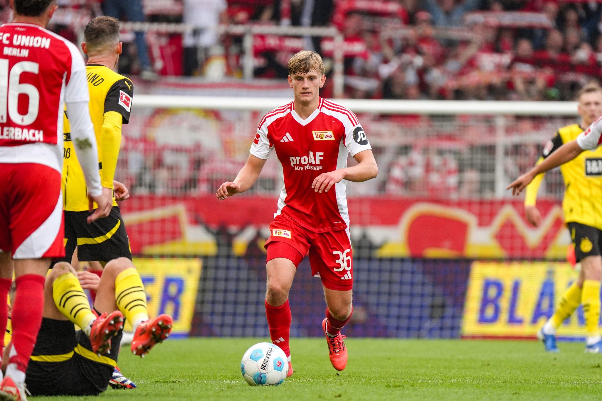 Ein Fußballspieler des 1. FC Union Berlin läuft mit dem Ball, während andere Spieler um ihn herum agieren.
