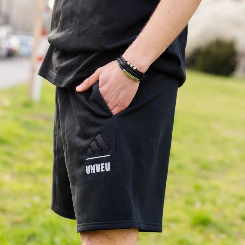 Ein Mann trägt schwarze Shorts mit einer seitlichen Tasche und einem Adidas-Logo.
