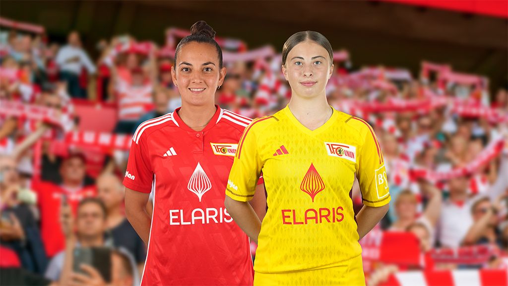 Zwei Frauen in Fußballtrikots stehen nebeneinander. Eine trägt ein rotes Trikot, die andere ein gelbes. Im Hintergrund sind Fans zu sehen.