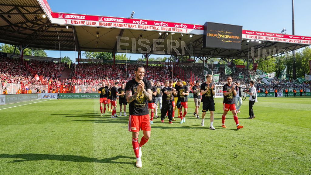 Fussballmannschaft feiert auf dem Platz vor jubelnden Fans in einem Stadion, während sie den Sieg genießt.