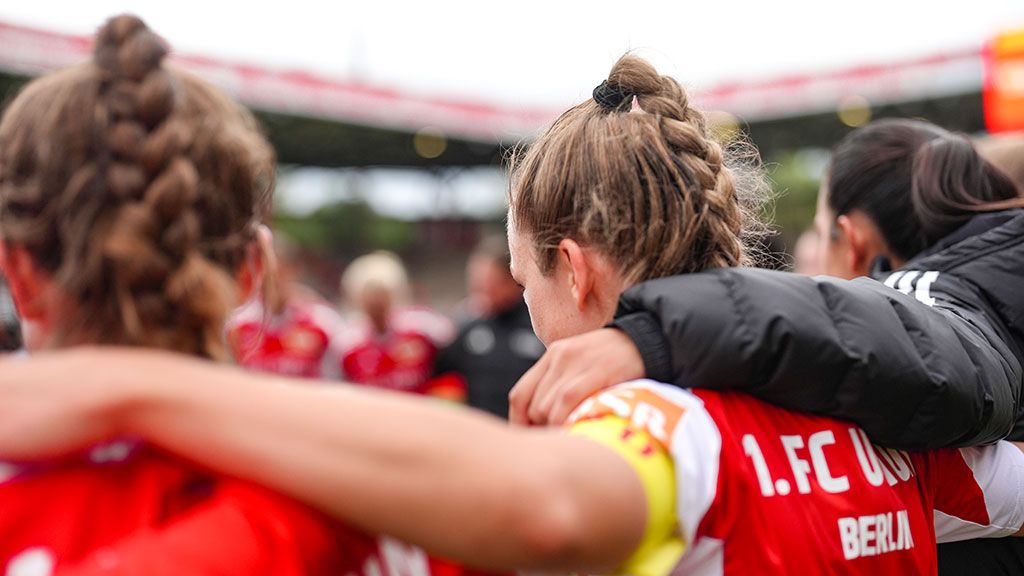 Players of 1. FC Union Berlin with braided hair embrace in a team circle.