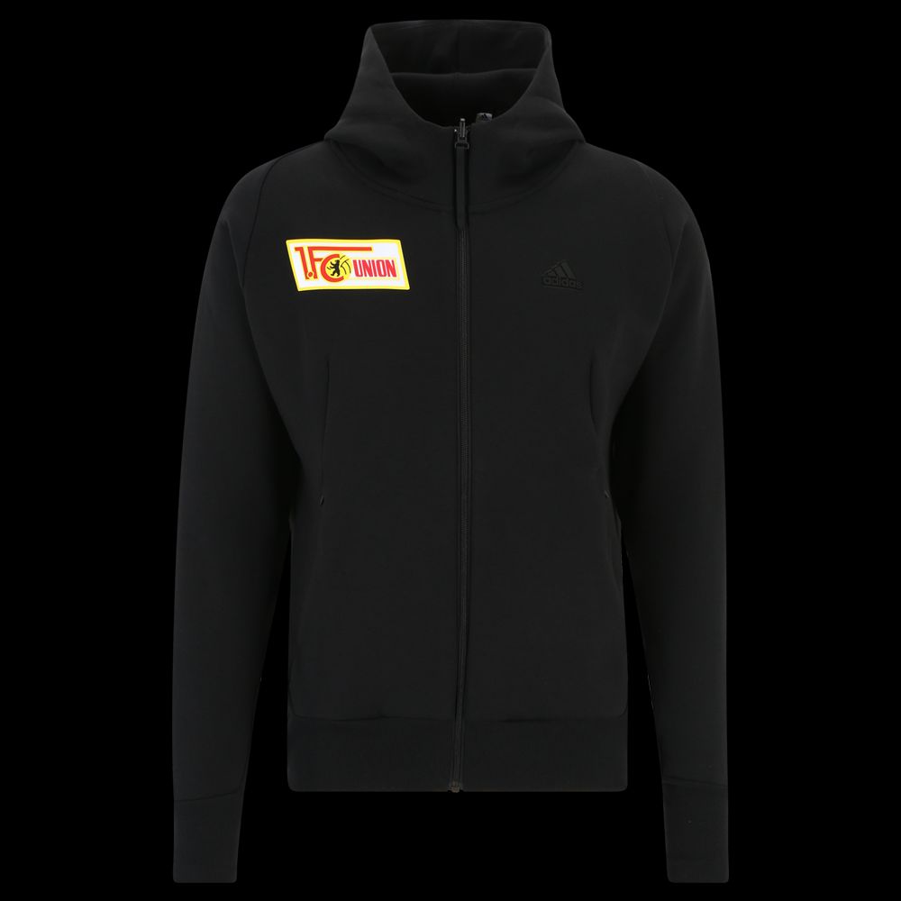 Schwarze Sportjacke. Sie hat eine Kapuze. Auf der linken Brust ist ein gelbes Logo von Union Berlin.