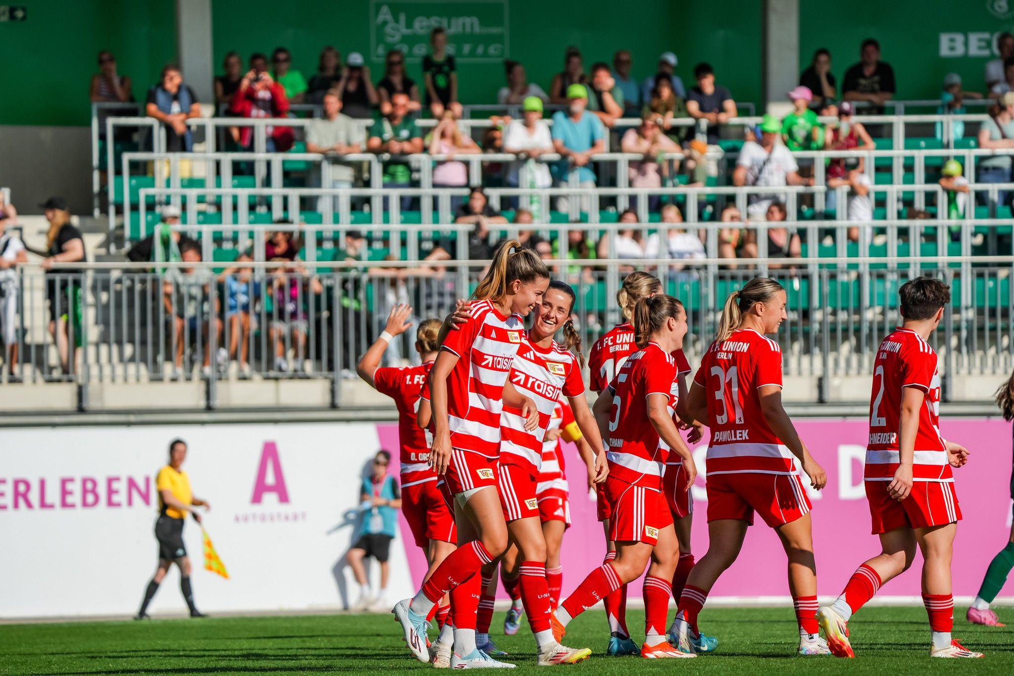 Fußballmannschaft in roten Trikots jubelt nach einem Tor vor jubelndem Publikum im Stadion.